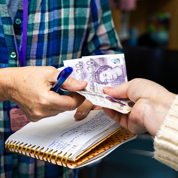 A member of the public handing over a cash donation at Eastwood Volunteer Bureau & Food Bank
